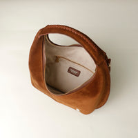 upper view of a opened Brown suede leather danilos handbag with visible brand logo on a light background