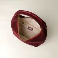 upper view of a opened suede leather danilos handbag with gold zipper on a white background