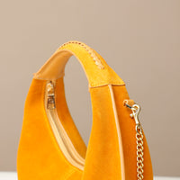 Yellow round suede leather danilos handbag with a gold chain on a beige background