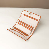 Front view of an open Danilos Leather jewelry organizer Mishka in brown with gold zippers and organizers in a beige background