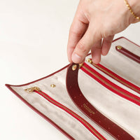 close-up view of the Danilos Leather jewelry organizer Mishka in red with gold zippers in a beige background