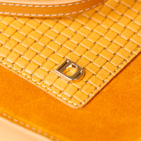 Close-up of a yellow woven leather product with a brand logo.