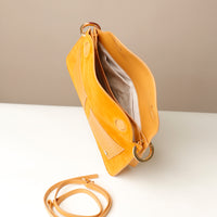 Open intetior of Yellow handbag with a strap on a white surface and beige background