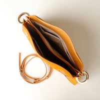 Open interior of Yellow handbag with a strap on a light background