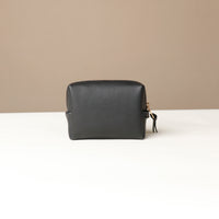 back view of a black Danilos leather toilet mini emma pouch on a beige background