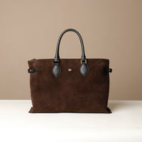 Brown leather handbag with black handles and accents on a beige background