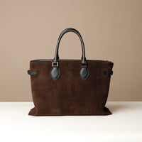Brown leather tote bag with black handles on a beige background