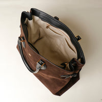 Brown leather handbag with gold accents on a beige background