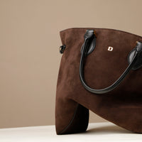 Brown suede handbag with black handle on a beige background