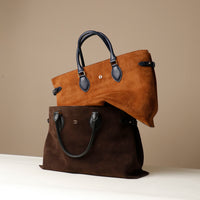 Two brown leather handbags stacked on a beige background