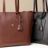 Two tote bags, one in brown and one in black, with shoulder straps and a zip-top closure.