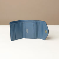 Blue wallet with a visible brand logo on a white surface and beige background