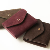 Three suede danilos wallets envelope like shape in different colors on a white background