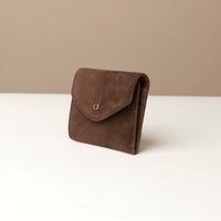 side of a Brown suede danilos wallets envelope shape on a white surface with a beige background