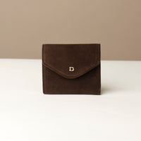 Brown suede danilos wallets envelope shape with a visible danilos logo on a white surface with a beige background