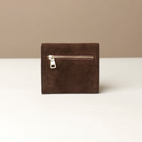 Brown suede danilos wallet with a gold zipper on a beige background