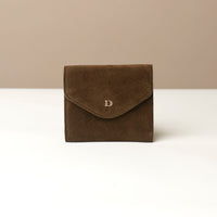 Green suede wallet envelope like shape with a danilos logo on a beige background