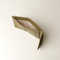 upper view of a green leather danilos wallet open upper view on a light beige background