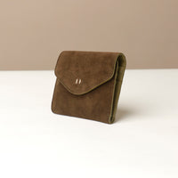 side of a green suede danilos wallet on a white surface with a beige background