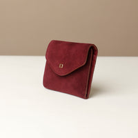 side of a Red suede wallet with a gold danilos logo on a white surface with a beige background