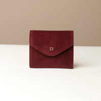 Red suede leather wallet envelope shape with a gold danilos logo on a white surface and beige background
