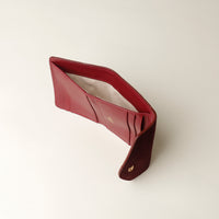 upper view of a Red leather danilos wallet opened on a light beige background