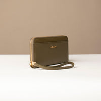 side view of a green Danilos wallet Carlota with a visible handle drop and gold zipper in a beige background