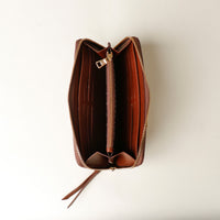 Brown leather wallet with a zipper on a light beige background