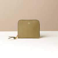 Front view of a green zurich sr danilos leather wallet with gold zipper over a beige background