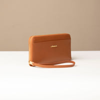 side view of a light brown Danilos wallet Carlota with a visible handle drop with gold zipper in a beige background