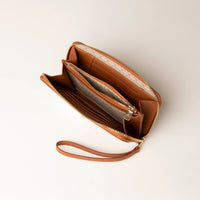 upper view of a open light brown Danilos wallet Carlota with a visible handle drop and gold zipper in a beige background