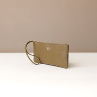 Brown leather clutch with a strap on a white surface and beige background