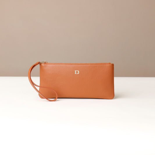 Brown leather clutch with a strap on a beige background