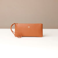 Brown leather clutch with a strap on a beige background