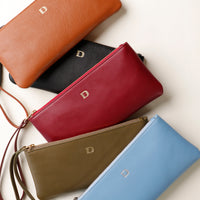 Five leather handbags in different colors on a light background