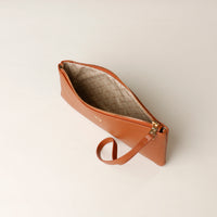 Brown leather clutch with a textured interior on a light beige background